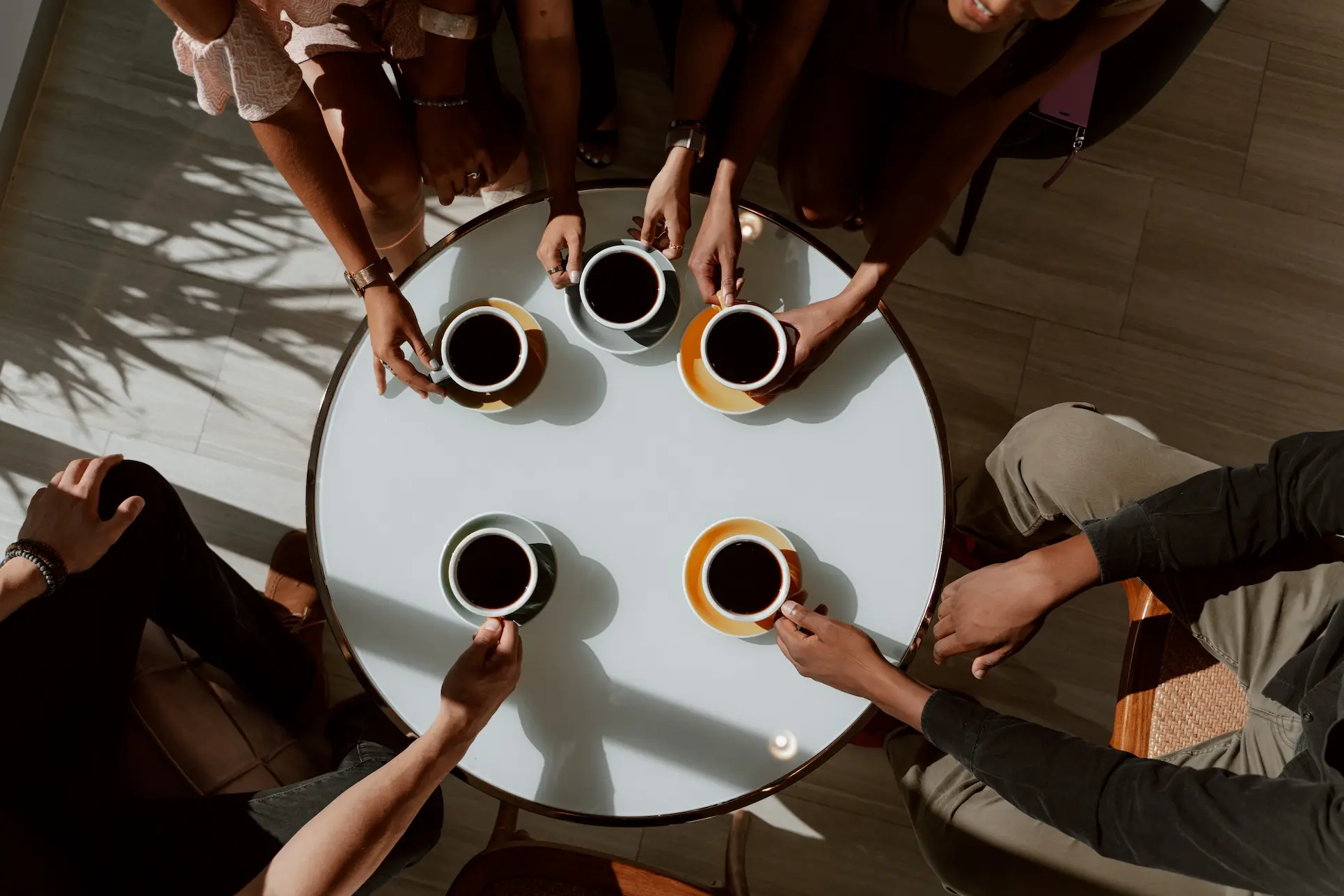 Egy kávézó asztal körül hosszú kávét fogyasztók 5 csésze kávéval.
